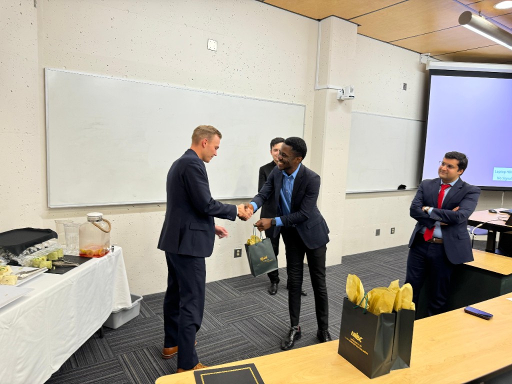 George Amoako shaking hands at a UNBC Investment Club recognition moment